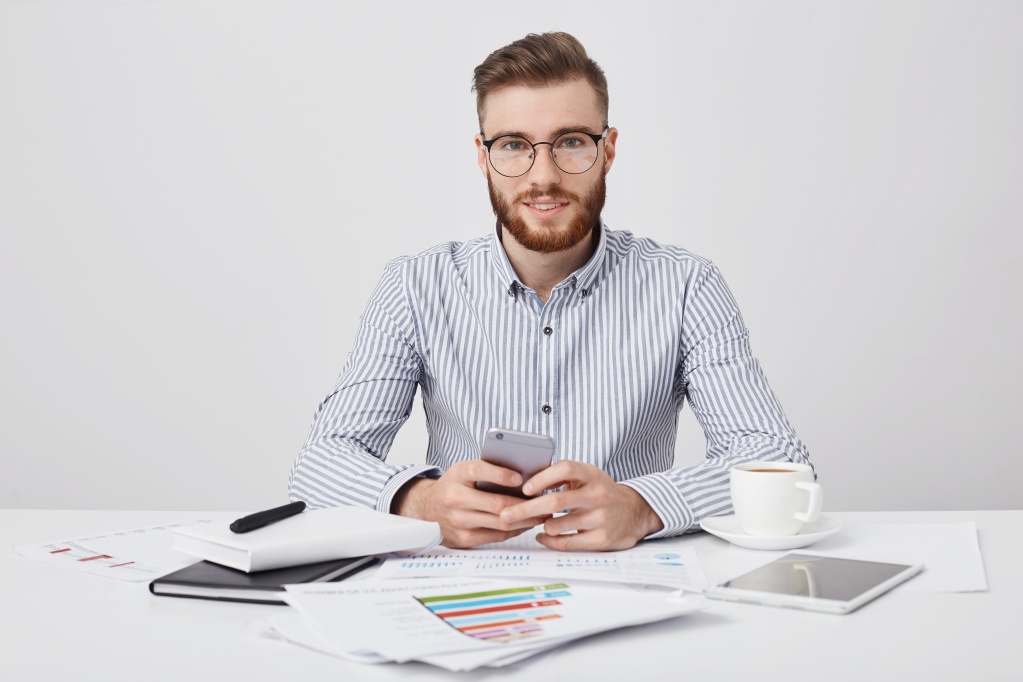 isolated-stdio-shot-pleasant-looking-stylish-male-manager-with-stubble-holds-smart-phone-as-messages-online.jpg